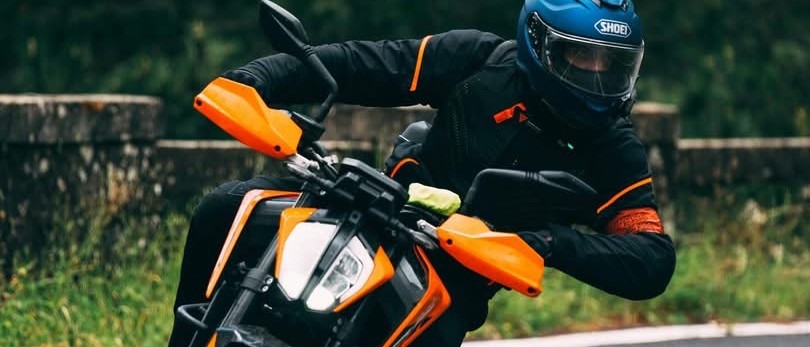 Motociclista in piega affronta una curva su strada, moto reale di Autoscuola Giulia